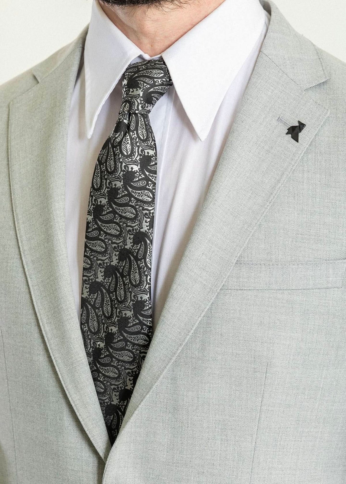 Men's light gray slim fit suit with patterned black tie, perfect for formal events and weddings.