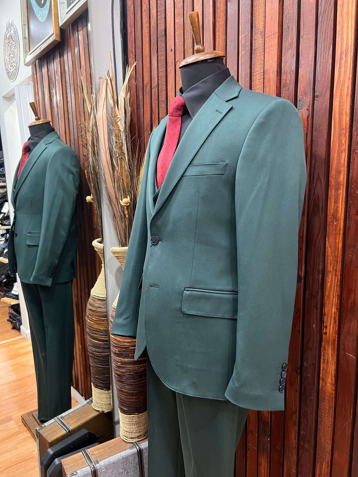 Men’s Forest Green 3-piece slim fit suit displayed in a boutique, featuring a stylish look with a red tie.