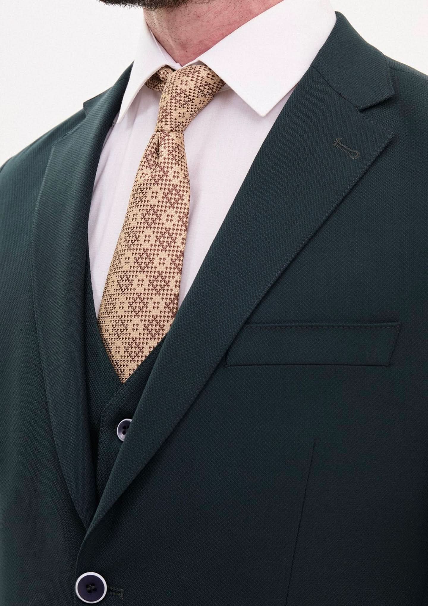 Close-up of a man in a hunter green 3-piece suit with a patterned tie, showcasing elegant formal wear.