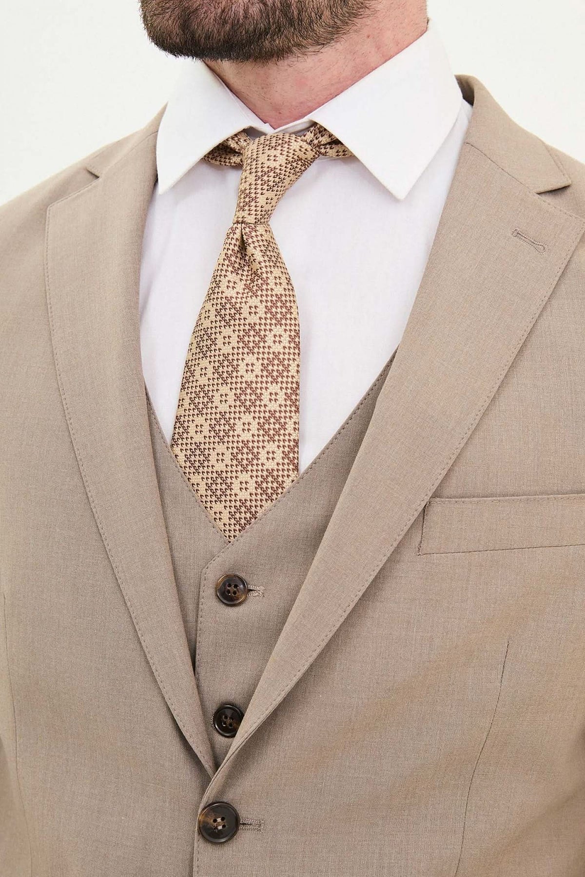 Close-up of a man's beige slim fit suit with a patterned tie, ideal for formal events and weddings.